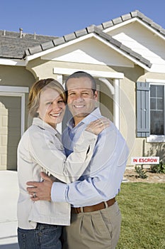 Couple Embracing In Front Of New House