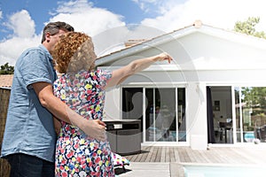 Couple embracing in front of new modern house, back view