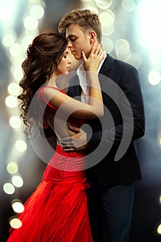 Couple Embracing in Love. Beautiful Girl and Handsome Man dancing in Romantic Hug over shining Lights Background. Boyfriend