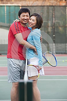 Couple embracing next to the tennis net