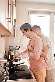 Couple embracing and preparing food together, while spending time in the kitchen