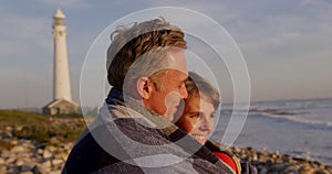 Couple embracing by the sea near a lighthouse