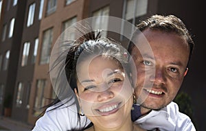 Couple embracing and smiling in front of their new first home.
