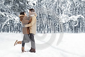 Couple Embracing Standing In Snowy Winter Forest In The Morning photo