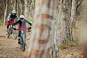 Couple of enduro mtb riders, woman and man going down the mtb trail in the forest of Barcelona