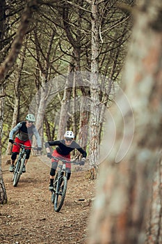 Couple of enduro mtb riders, woman and man going down the mtb trail in the forest of Barcelona