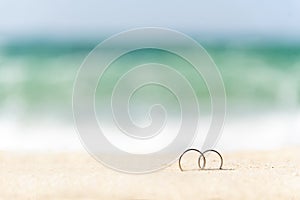Couple engagement wedding rings on summer tropical sand beach with copy space. Display design for honeymoon travel agency concept
