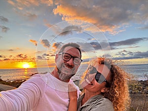 Couple enjoy outdoor leisure activity together smiling and taking selfie at the beach. Young mature man and woman smile at the