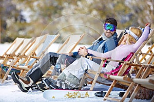 Couple enjoy in sun loungers on ski terrain