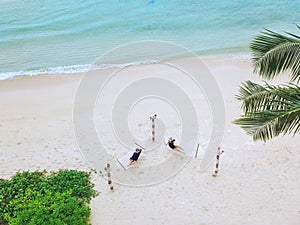 A couple enjoying a beach vacation at a tropical resort with a beautifully landscaped coastal pool at sunset. honeymoon