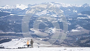 Couple enjoying beautiful alpine view with snow mountains during winter, Slovakia, Europe