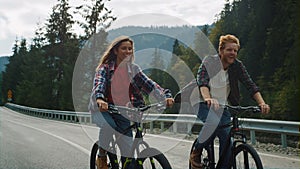 Couple enjoying bike ride in mountains. Cyclists exercising on forest highway.