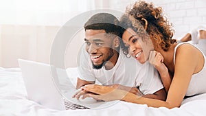 Couple enjoying content on a laptop in bed