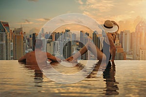 Couple enjoying Dubai skyline with skyscrapers architecture from hotel infinity pool at sunset. luxury vacation and travel. United