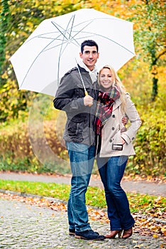 Couple enjoying fall day having walk despite the rain