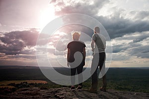 Couple enjoying fantastic moments during sunset . Young pair of hikers on the peak of rock empires park and watch over valley.