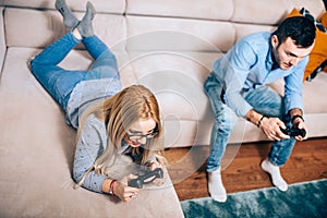 Couple enjoying games on general gaming console sitting on couch in free time. Details of modern lifestyle