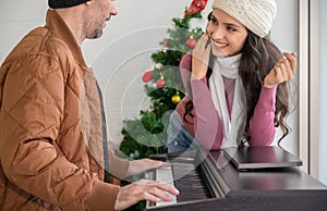 Couple enjoying great time in living room with piano. Man playing piano and singing for woman. Celebrating winter holidays