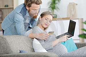 couple enjoying online shopping sitting on sofa at home photo