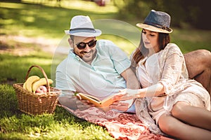 Couple enjoying picnic time outdoor reading book