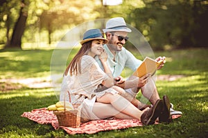 Couple enjoying picnic time outdoor reading book