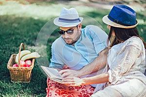 Couple enjoying picnic time outdoor reading book