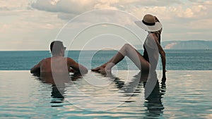 Couple enjoying romantic sea view in infinity swimming pool at luxury resort