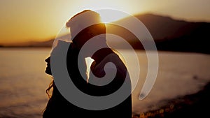 Couple enjoying a romantic sunset evening together on the beach. Couple silhouette at the beach. Sunset light. Smile.