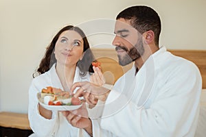 Couple Enjoying Sandwiches Having Breakfast Sitting In Bedroom, Selective Focus