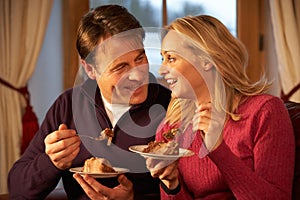 Couple Enjoying Slice Of Cake Sitting On Sofa