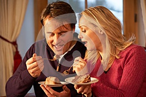 Couple Enjoying Slice Of Cake Sitting On Sofa