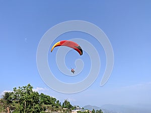 Couple enjoying the thrill of paragliding in a picturesque grassy field in Pokhara, Nepal