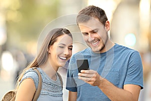 Couple enjoying using a smart phone on the street