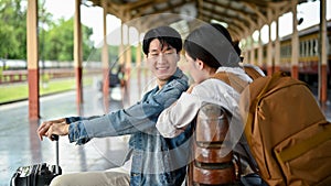 Couple enjoys talking on a bench on the platform before boarding the train together