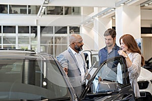 Couple examining new auto with car dealer