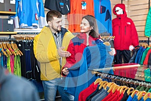 Couple examining track jackets in sports clothes store