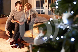 Couple Exchanging Gifts By Christmas Tree