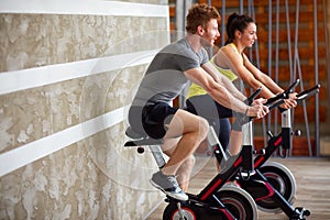 Couple exercises on bike in gym