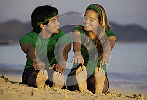 Couple exercising on beach at sunrise