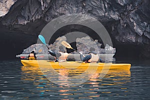 Couple exploring cave on kayak and taking photograps in the boat. Ha Long Bay, Vietnam, Cat Ba Island