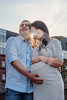 Couple family in the expectation of a baby hugging in the city