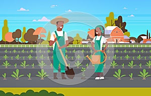 Couple farmers planting seedlings plants vegetables african american man woman gardeners using shovel watering can eco