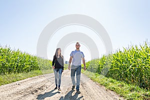 Couple of farming entrepreneurs walking on a farm in a corn field