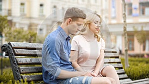Couple feeling awkward, sitting on bench in silence, crisis in relationship