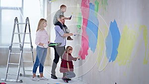 couple with female and male children with down syndrome on fathers shoulder paint walls with construction rollers