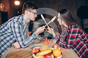 Couple fight with wooden spoons on the kitchen