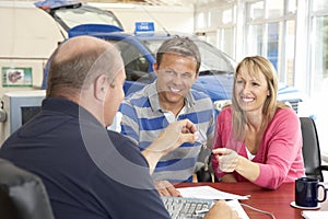 Couple filling in paperwork in car showroom