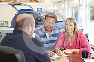 Couple filling in paperwork in car showroom