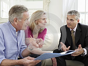 Couple With Financial Advisor At Sofa