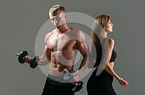Couple of fit bodybuilders, muscular man and beautiful sexy girl with dumbbells. Muscular sexy couple body. Sport couple
